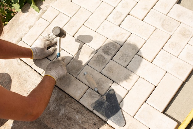 Verlegung von grauen Betonpflasterplatten im Innenhof des Hauses auf einer Sandgrundlage