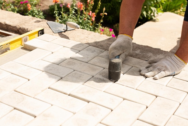 Verlegung von grauen Betonpflasterplatten im Innenhof des Hauses auf einer Sandgrundlage