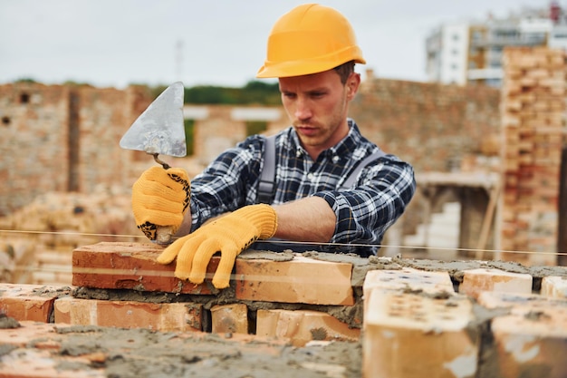 Verlegung von Ziegeln Bauarbeiter in Uniform und Sicherheitsausrüstung haben Arbeit am Bau