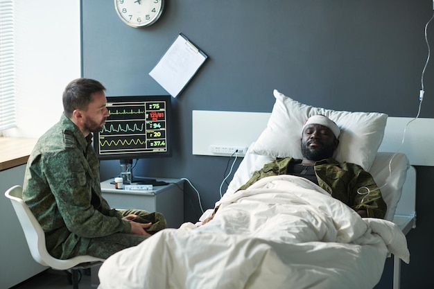 Foto verletzter afroamerikanischer soldat mit bandagiertem kopf, der im bett liegt
