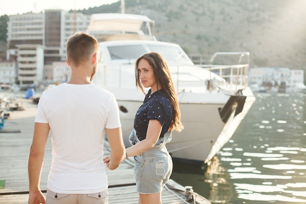 Verliebte gehen auf dem Pier vor der Kulisse von Yachten und Booten.