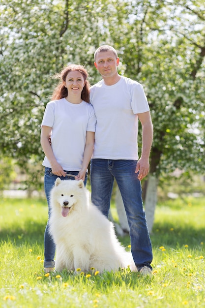 Verliebte Menschen gehen mit einem Hund auf dem Lande spazieren.