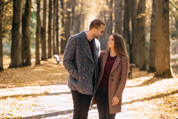 Foto verliebte paare, die im herbst im park händchen haltend spazieren gehen