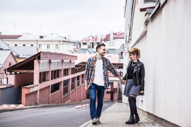 Verliebtes Paar, das die Straße einer modernen Stadt entlang geht