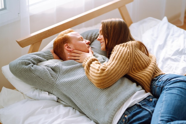 Verliebtes Paar entspannt sich zu Hause auf dem Bett, während sie sich umarmen Valentinstag Urlaubskonzept