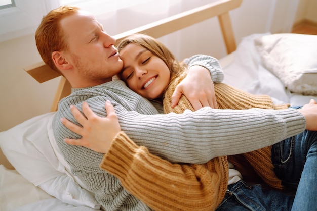 Verliebtes Paar entspannt sich zu Hause auf dem Bett, während sie sich umarmen Valentinstag Urlaubskonzept