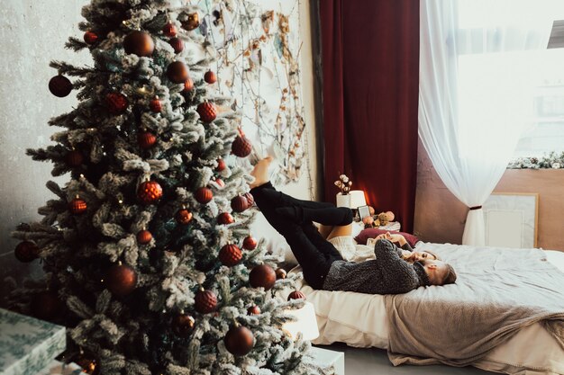 Verliebtes Paar nahe dem Weihnachtsbaum, der auf dem Bett liegt