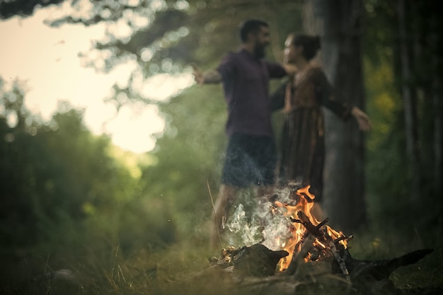 Verliebtes Paar umarmt sich auf verschwommenem Hintergrund am Lagerfeuer