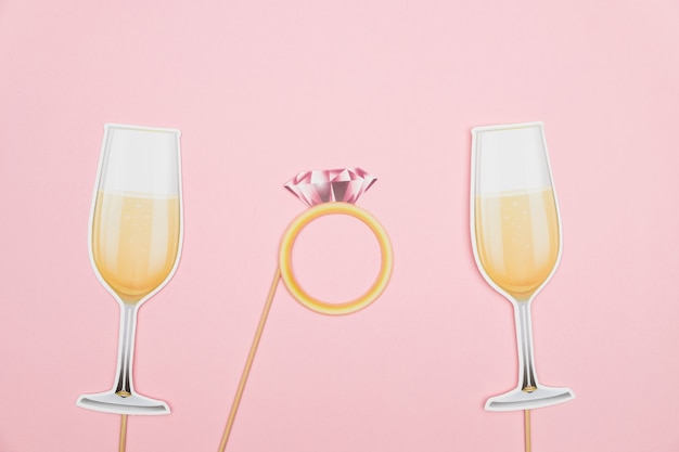 Foto verlobungsring des valentinstagkonzepts und champagnergläser von papierstütze auf rosa hintergrund