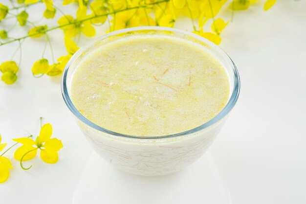 Vermecelli Payasam ou Kheer, prato doce principal do sul da Índia feito com aletria, leite, açúcar e nozes secas e arranjado com flor de chuva dourada no fundo branco, foco seletivo.