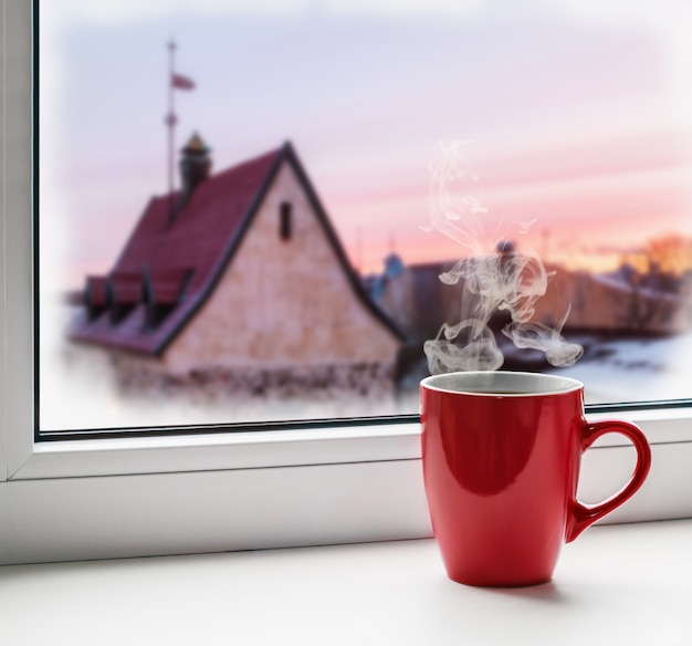 Vermelha xícara de café no peitoril da janela