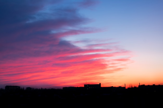 Vermelho rosa e azul brilhante pôr do sol sobre a cidade