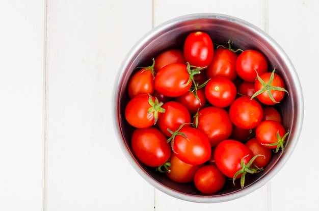 Vermelho tomate cereja maduro na mesa de madeira.