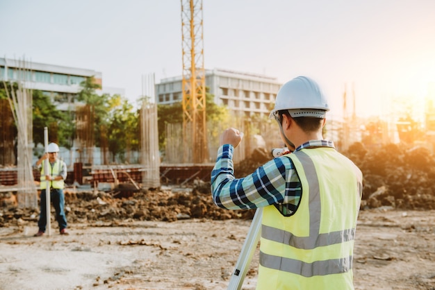 Vermessungsingenieure arbeiten auf der Baustelle mit Theodolit zusammen.