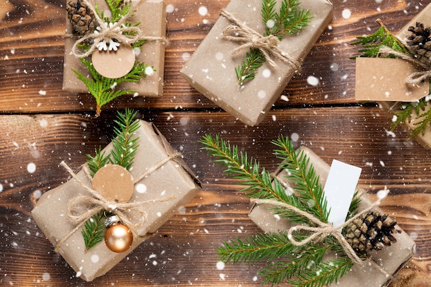 Verpacken Sie ein Geschenk zu Weihnachten und Neujahr in umweltfreundlichen Materialien: Kraftpapier, lebende Tannenzweige, Zapfen, Bindfäden, Schnee. Tags mit Mock-up, natürliches Dekor, handgefertigt, DIY. Festliche Stimmung. Flach, Hintergrund