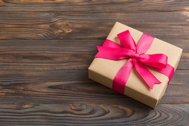 Verpacktes Weihnachts- oder anderes Feiertagshandgemachtes Geschenk in Bastelpapier mit farbigem Band Präsentkartondekoration des Geschenks auf der Tischplatte mit Kopierraum