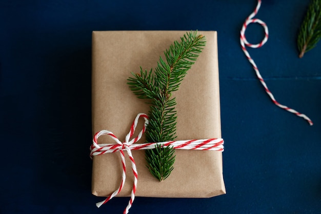 Verpackung von Weihnachtsgeschenken in Papier und natürlichen Tannenzweigen auf blauem Holzhintergrund