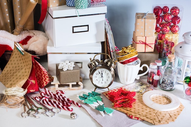 Foto verpackungsboxen, geschenke in kraftbeige-vintage-geschenkpapier. kranzstechpalmenbeere auf grauem wandhintergrund. konzept der vorbereitung auf neujahrs- und weihnachtsferien