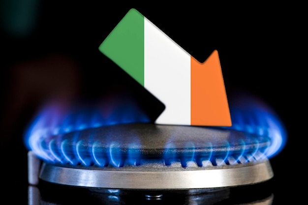 Verringerte Gasversorgung in Irland Ein Gasherd mit brennender Flamme und einem Pfeil in den Farben der irischen Flagge, der nach unten zeigt Konzept der Krise im Winter und Mangel an Erdgas Heizsaison