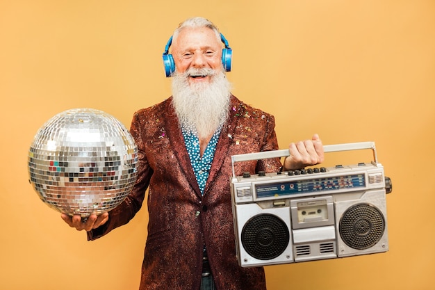 Foto verrückter hipster-mann, der musik mit kopfhörern hört, während er discokugel und vintage-stereo - party-konzept hält