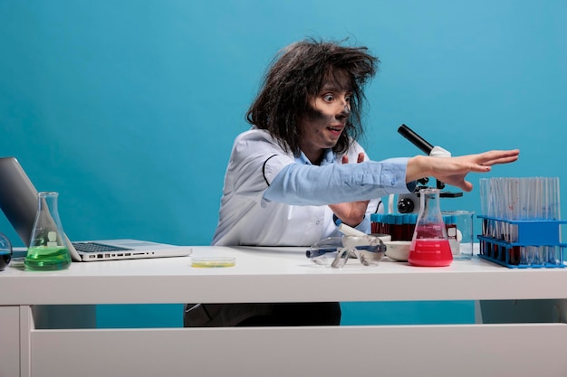 Verrückter Wissenschaftler mit albernem Aussehen, der während der Arbeit im Labor Glasreagenzgläser im Regal sitzt. Verrückte Frau, die in der Wissenschaft arbeitet und einen amüsanten Gesichtsausdruck hat, der neue Formeln experimentiert.