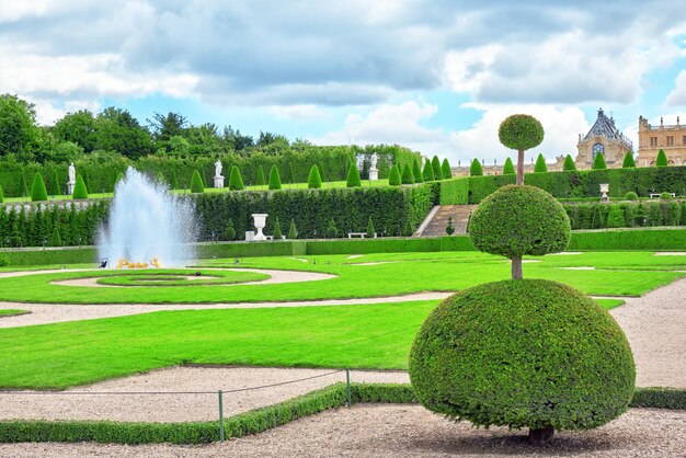 VERSAILLES FRANKREICH 2. JULI 2016 Brunnen in der Nähe des Blumenbeets in einem berühmten Garten von Versailles Chateau de Versailles