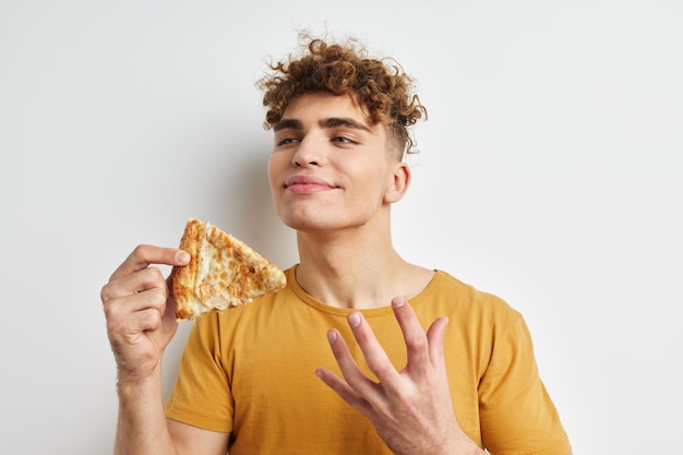 Versauter Kerl in einem gelben T-Shirt, der den unveränderten Pizza-Lebensstil isst