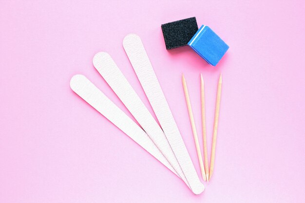 Foto verschiedene abrasive nagellackfeilen und holzstäbchen auf rosa hintergrund maniküre und pediküre