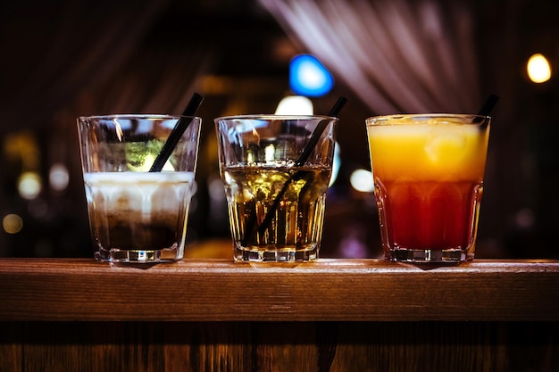 Verschiedene alkoholische Cocktails mit Eis in einer Bar auf einem Holztisch