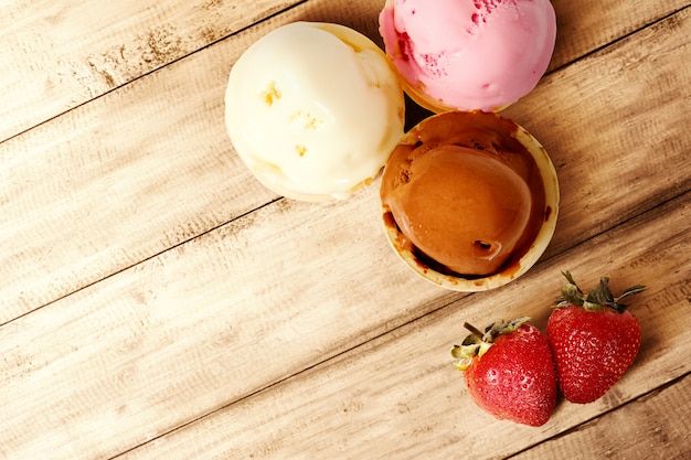 Verschiedene Arten des Eiscremearomas und der Erdbeere tragen auf Holztisch Früchte