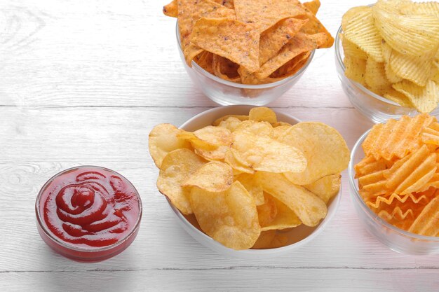 Verschiedene Arten von Chips in Schalen und roter Sauce