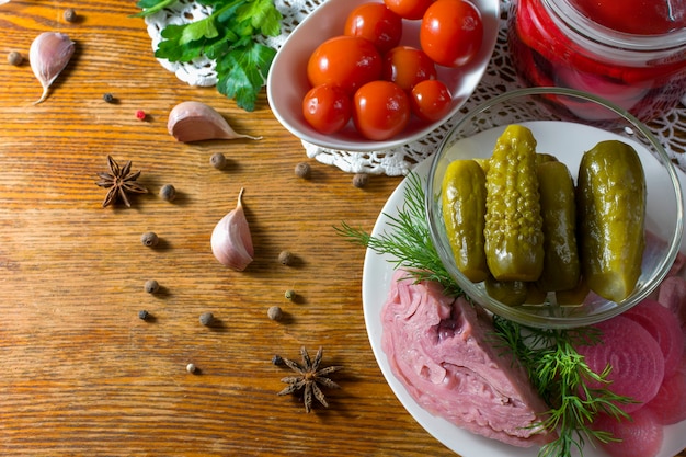 Verschiedene Arten von eingelegtem Gemüse. Eingelegte Gurken, Tomaten, Kohl, Pfeffer, Gemüse, Zwiebeln und Knoblauch werden auf einem Tisch im alten Stil mit handgefertigter Tischdecke serviert. Hausgemachtes fermentiertes Gemüse