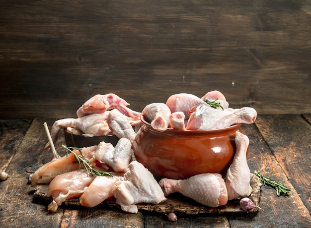 Verschiedene Arten von rohem Hühnerfleisch mit Kräutern in einer Schüssel auf Holztisch.