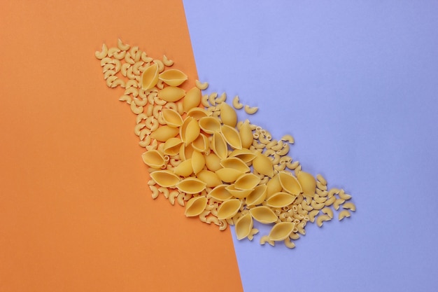 Verschiedene Arten von rohen italienischen Nudeln auf braunem lila Hintergrund.