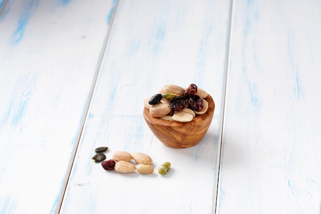 Foto verschiedene beeren, nüsse und samen in einer holzschale auf einem hellen holztisch.