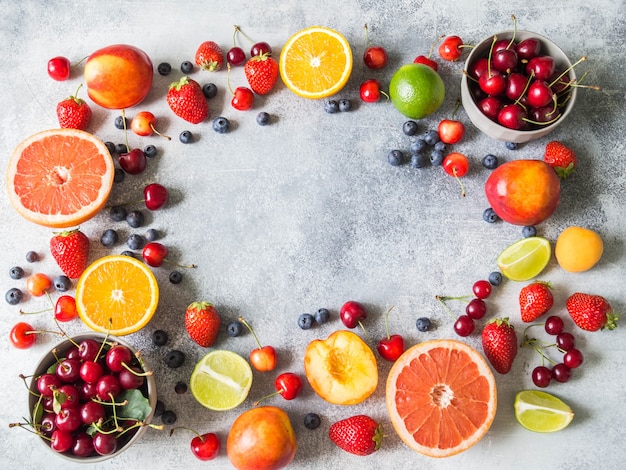 Verschiedene beeren und früchte auf einem grauen rahmenhintergrund