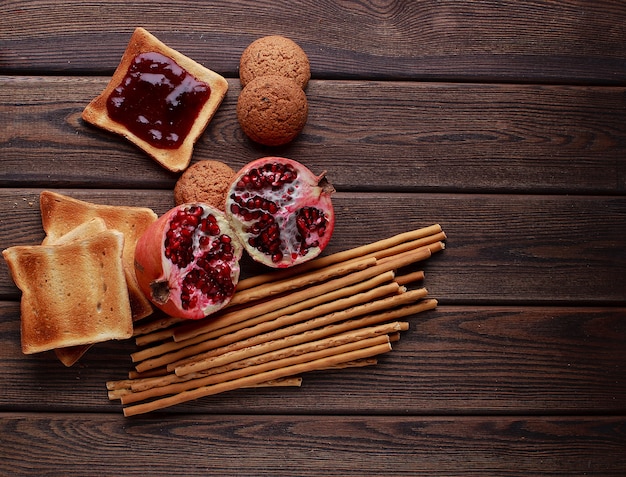 Verschiedene Brötchen mit frischem Brot und Weizenährchen auf braunem Vintage-Hintergrund