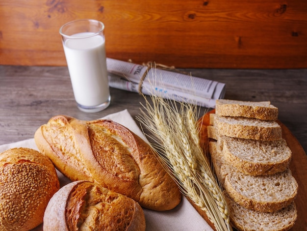 Verschiedene Brote und ein Glas Milch auf Holztisch