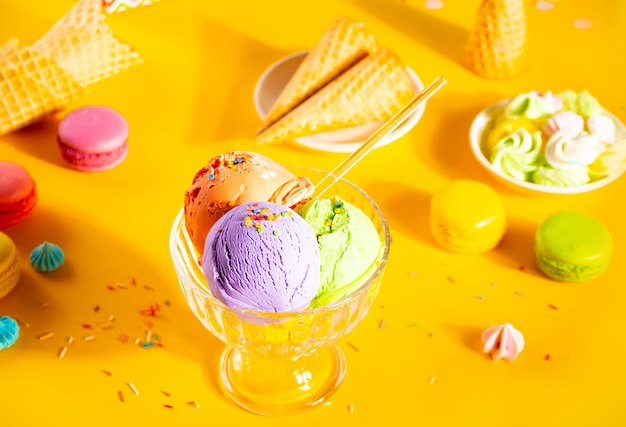 Verschiedene bunte Eiskugeln oder Bälle Eisbecher mit Waffeln Makronen auf gelbem Hintergrund