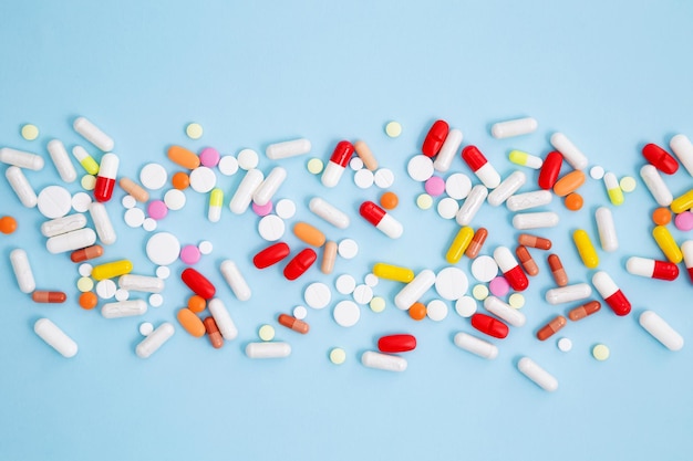 Verschiedene bunte Medikamententabletten und -kapseln auf blauem Hintergrund Konzept des Gesundheitswesens und der Medizin