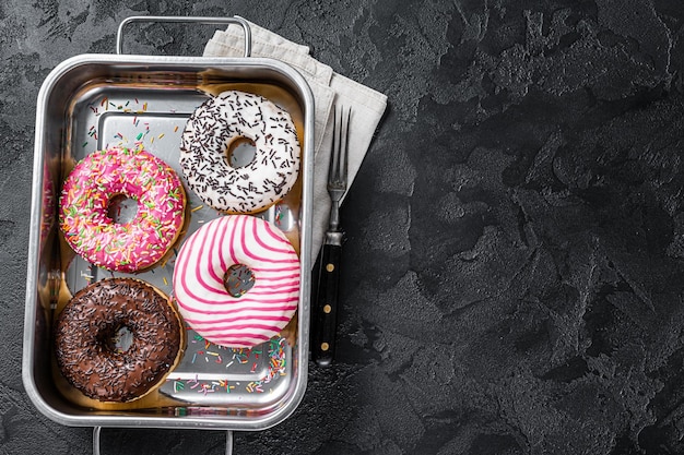 Verschiedene Donuts mit Schokolade, rosa glasiert und Streuseln Donut. Schwarzer Hintergrund. Ansicht von oben. Platz kopieren.