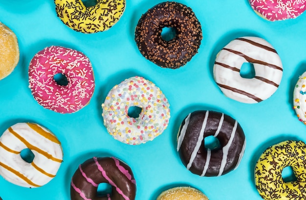 Verschiedene Donuts mit verschiedenen Füllungen und Zuckerguss auf einem blauen Rücken