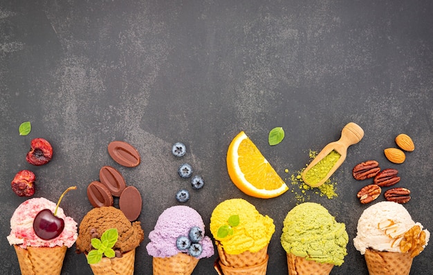 Foto verschiedene eiscremearomen in zapfen heidelbeeren, grünem tee, pistazien, mandeln, orangen und kirschen auf dunklem stein