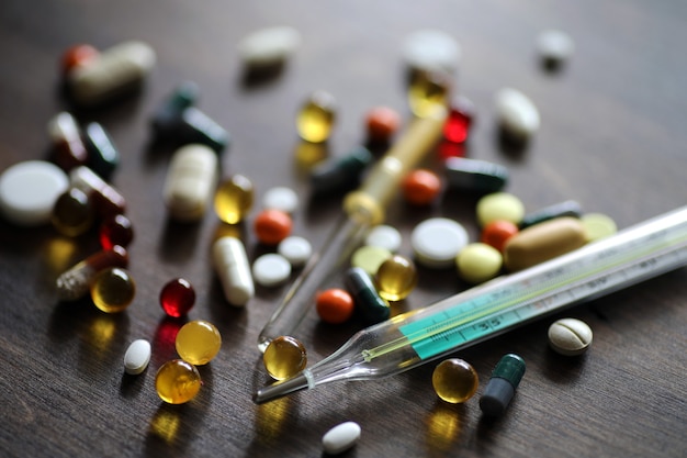 Verschiedene farbige Medikamente und Tabletten auf einem Holzstrukturtisch