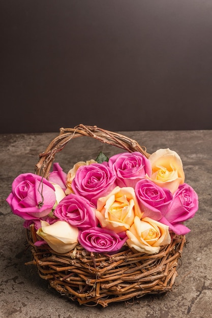 Verschiedene frische mehrfarbige Rosen im Weidenkorb. Das festliche Konzept für Hochzeiten, Geburtstage, 8. März, Mutter- oder Valentinstag. Grußkarte, Marmorhintergrund