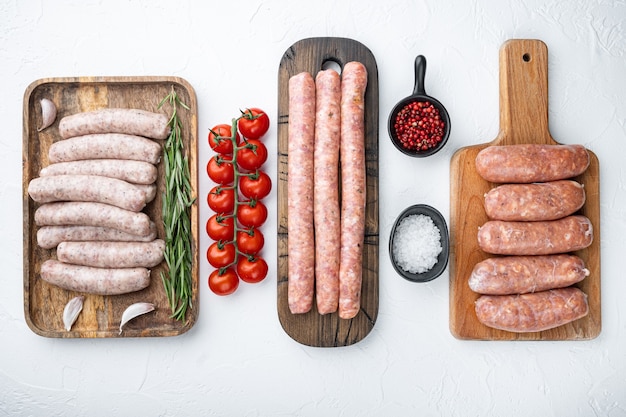 Verschiedene frische rohe Wurstwaren aus Schweinefleisch, Rindfleisch und Hühnchen, Draufsicht, auf weißem Tisch