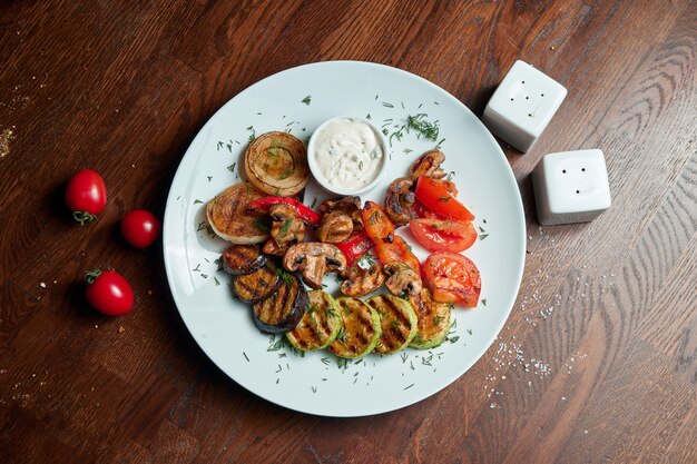 Foto verschiedene gegrillte gemüse - pilze, zucchini, paprika, mais in einer keramikplatte. vegetarischer warmer salat. gesundes essen