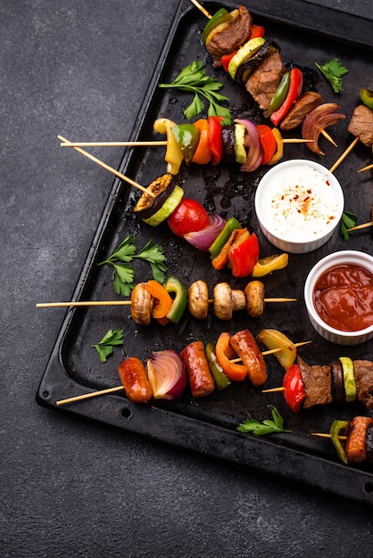 Verschiedene gegrillte Kebabs mit Fleisch, Pilzen, Würstchen und Gemüse am Spieß