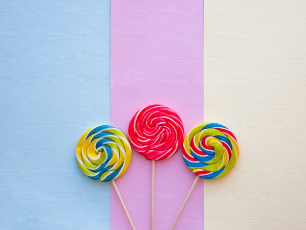 Verschiedene geschmackvolle bunte Süßigkeiten auf Pastellfarbhintergrund.