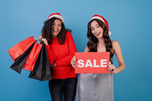 Verschiedene glückliche Frauen mit bunten Einkaufstaschen und rotem copyspace Verkaufszeichen